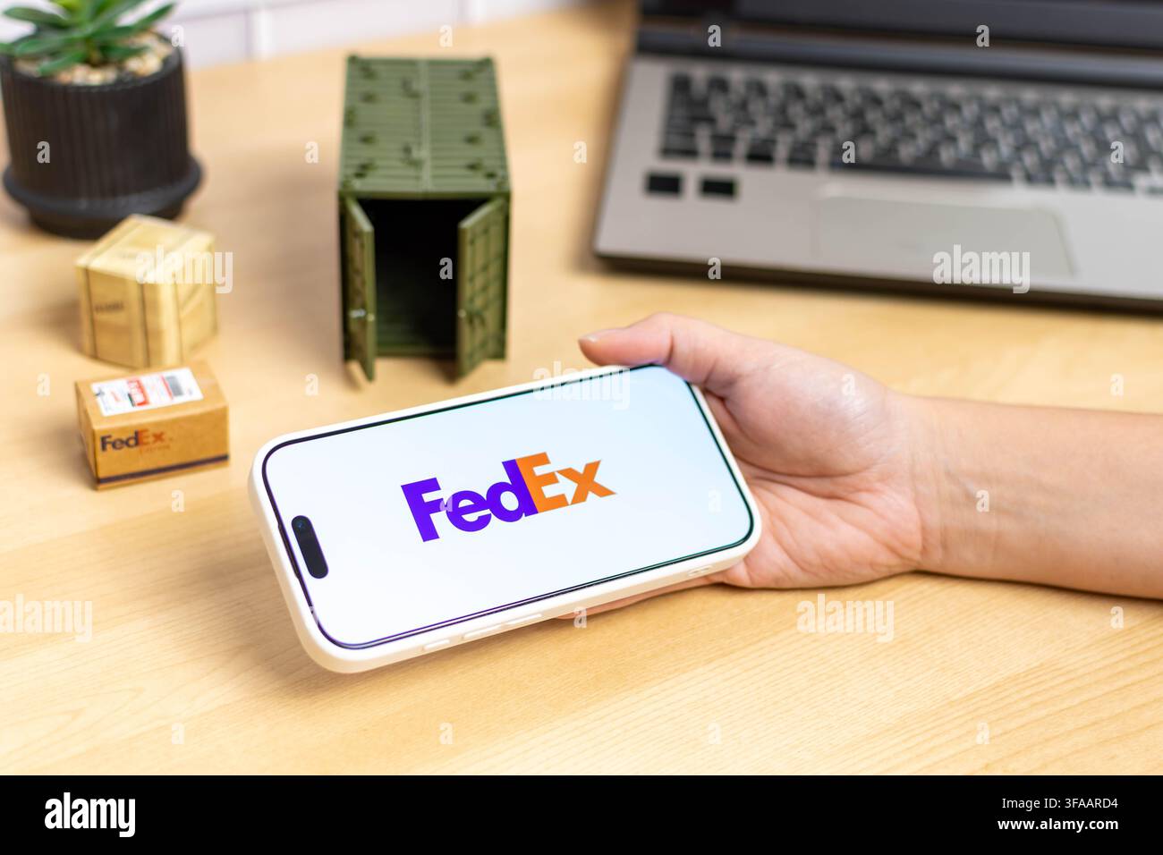 Hand, die ein iPhone mit dem FedEx-App-Logo hält. Stockfoto