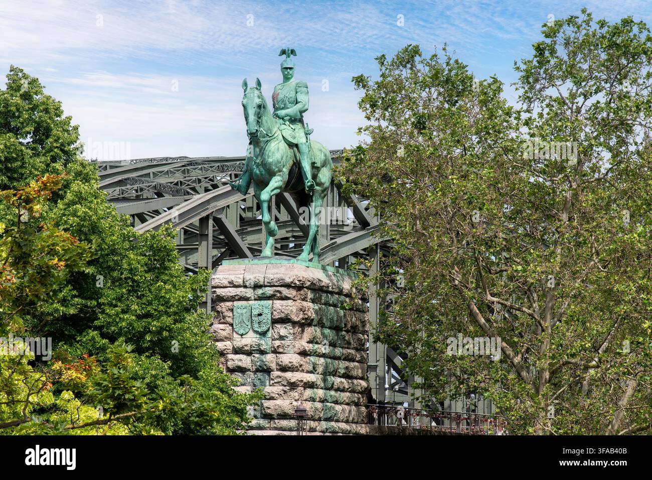 Köln, Deutschland-2. Juni 2026; Niedrigwinkelaufnahme der Reiterstatue von Kaiser Friedrich III mit im Hintergrund der Spannweite der Hohenzollernbrücke Stockfoto