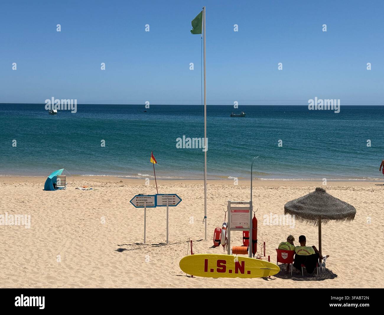 SALEMA, PORTUGAL - 10. Juli 2025: Rettungsschwimmer halten von einer Strandstation mit der Markierung „I.S.N.“ unter einer grünen Sicherheitsflagge am Sandstrand in Salema Wache Stockfoto