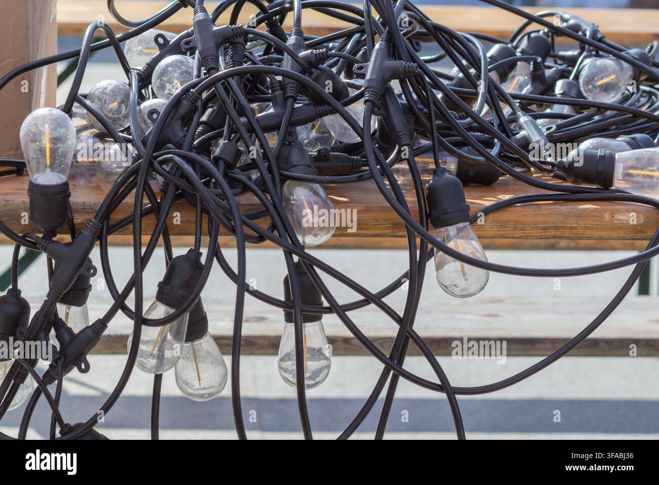 Dekorative Lichterketten mit freiliegenden Glühbirnen und verwirrten elektrischen Kabeln. Stockfoto