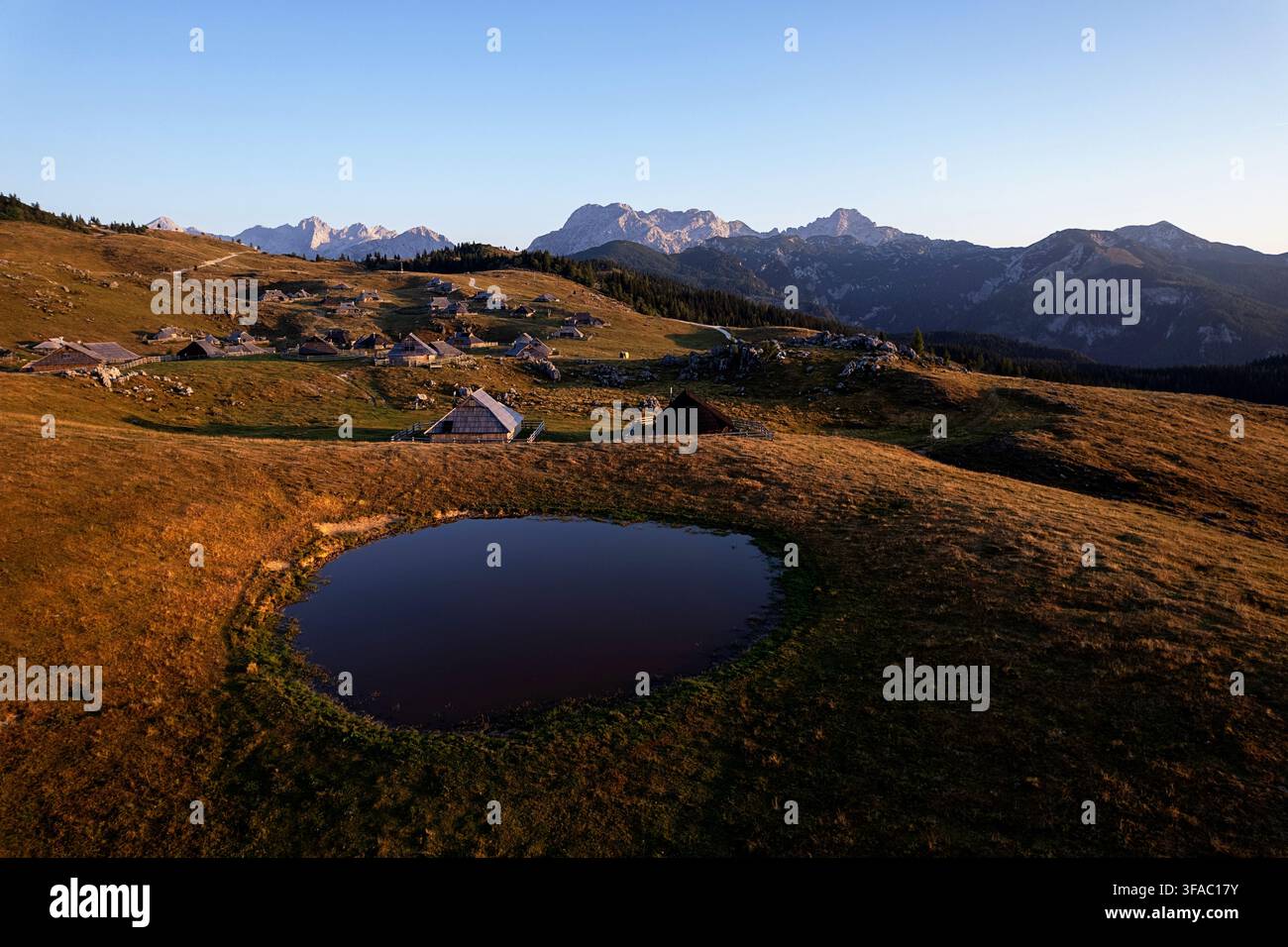 Traditionelle Holzhütten von Hirten, die auf den grünen alpinen Weiden der malerischen Bergplateau-Landschaft der Velika Planina in Slowenien stehen. Stockfoto