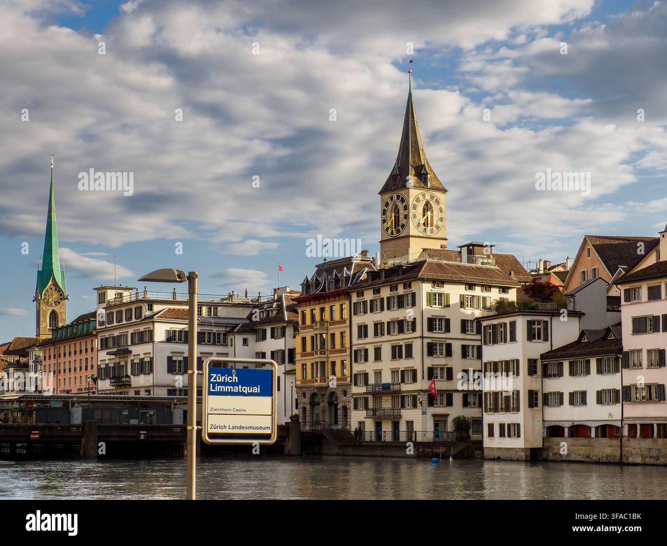 Historische Ufergebäude und der Glockenturm der St. Peters Kirche entlang der Limmat in Zürich Stockfoto