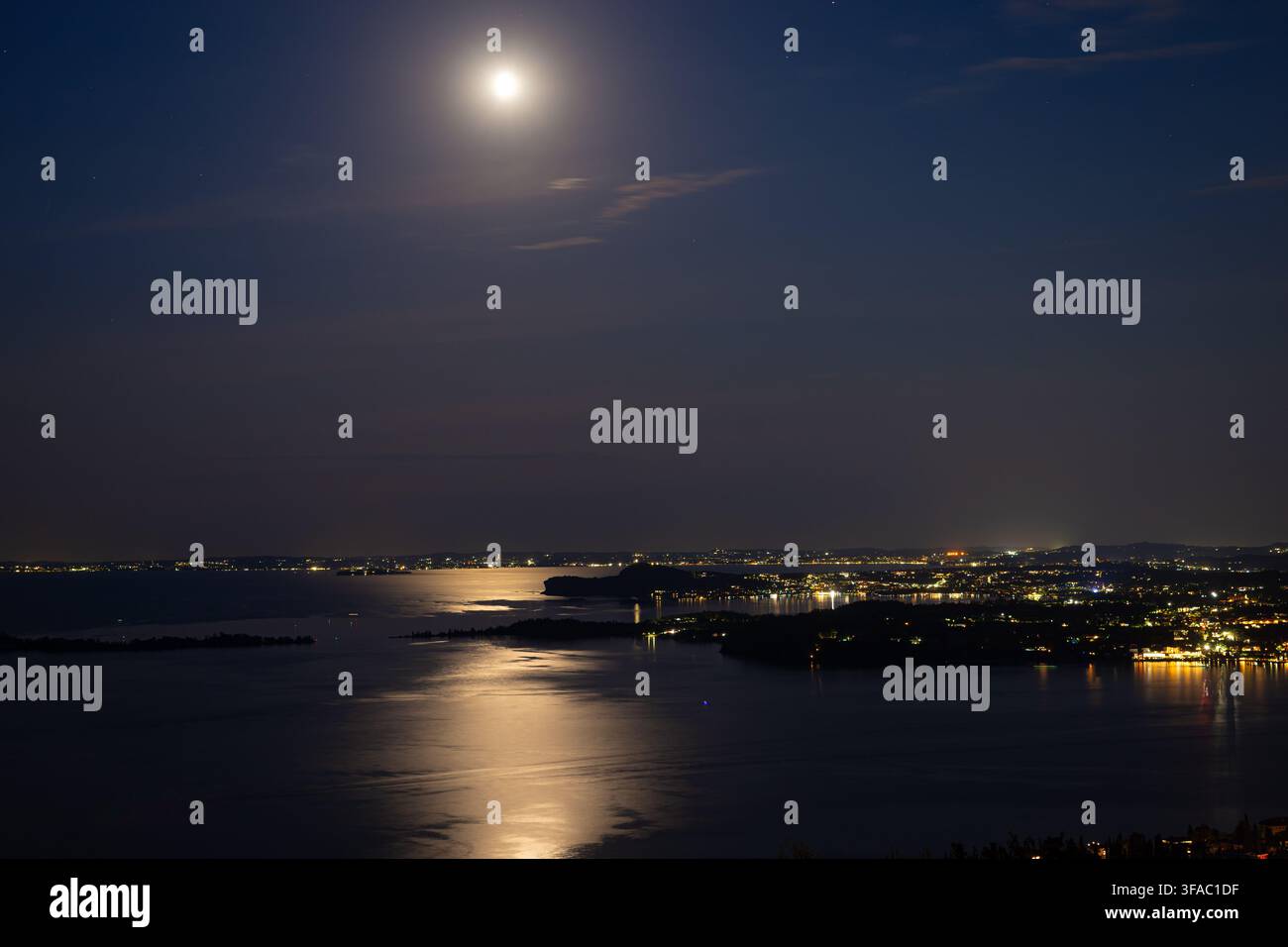 Pittoreske Ansicht des Vollmonds über dem Gardasee, Italien mit Mondlichtreflexion auf ruhigem Wasser Stockfoto