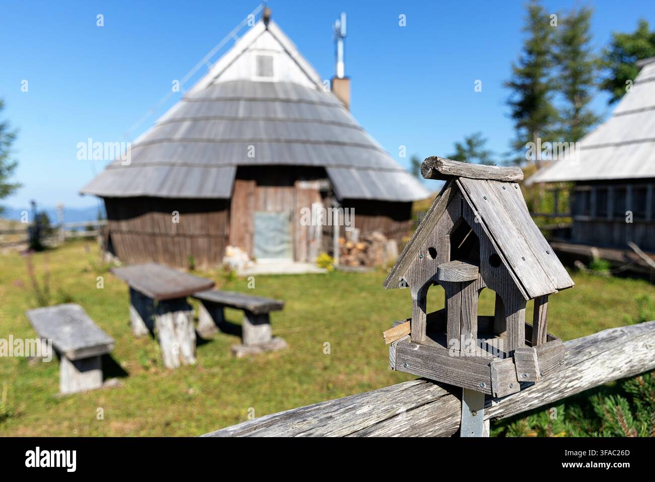 Handgefertigtes Holzhäuschen im traditionellen Hirtenlager umgeben von rustikalen Holzhäusern auf dem Hochplateau Velika Planina, Slowenien. Stockfoto