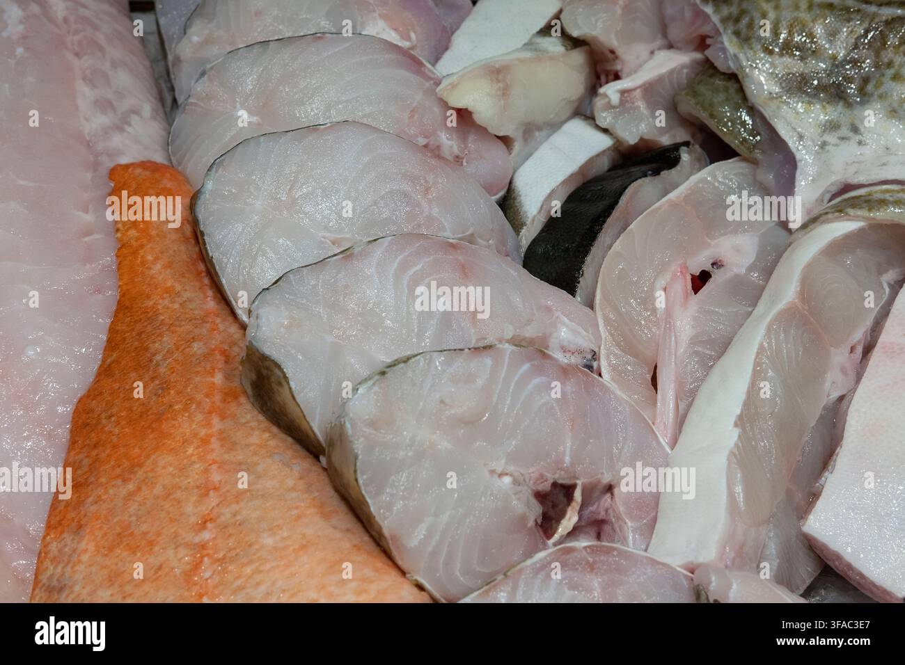 Fischauswahl in einem Fischmarkt, verschiedene rohe Filets und sauber portionierte Schnitte zur Verkaufsbereitstellung, Konzept für frische Lebensmittel oder Feuchtmärkte Stockfoto