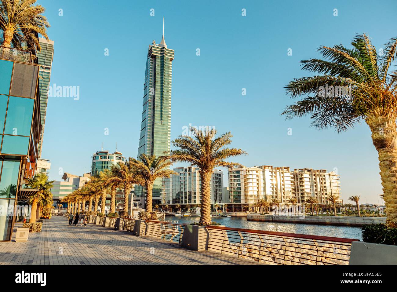 Manama, Bahrain - 13. Juni 2026: Blick auf die moderne Skyline des Bahrain Financial Harbour mit seinem ikonischen Wolkenkratzer, Palmen, die das Wasser säumen Stockfoto