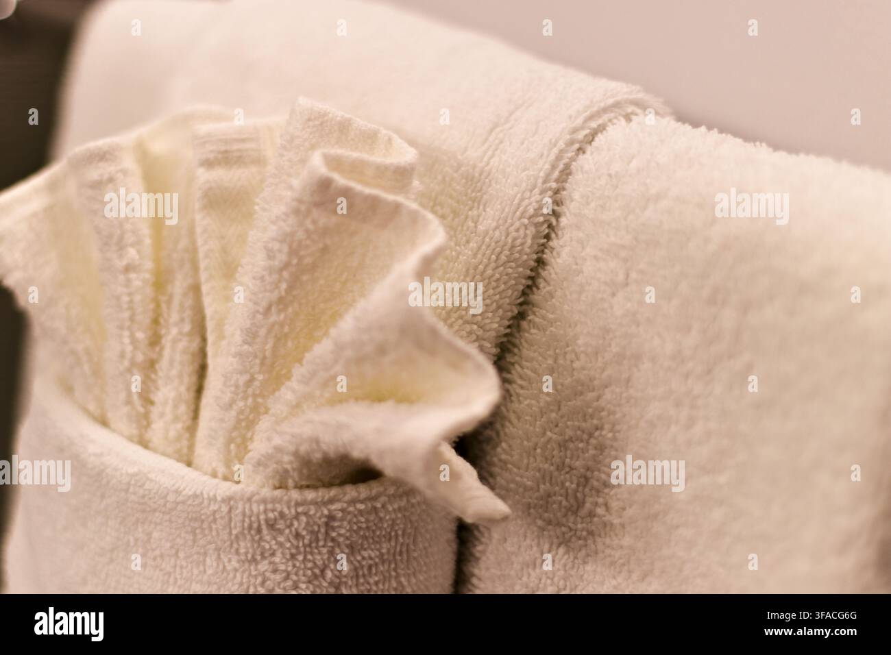 Nahaufnahme eines weichen, gefalteten weißen Handtuchs mit strukturiertem Rand. Detail zeigt plüschigen, sauberen Stoff, perfekt für Spa- oder Hotelumgebungen. Schlägt Entspannung vor, com Stockfoto