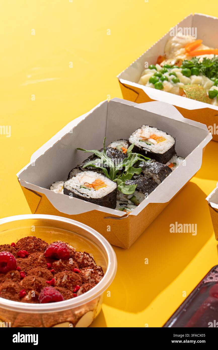 Sushi-Rollen in einer Papierversandbox auf Gelb Stockfoto
