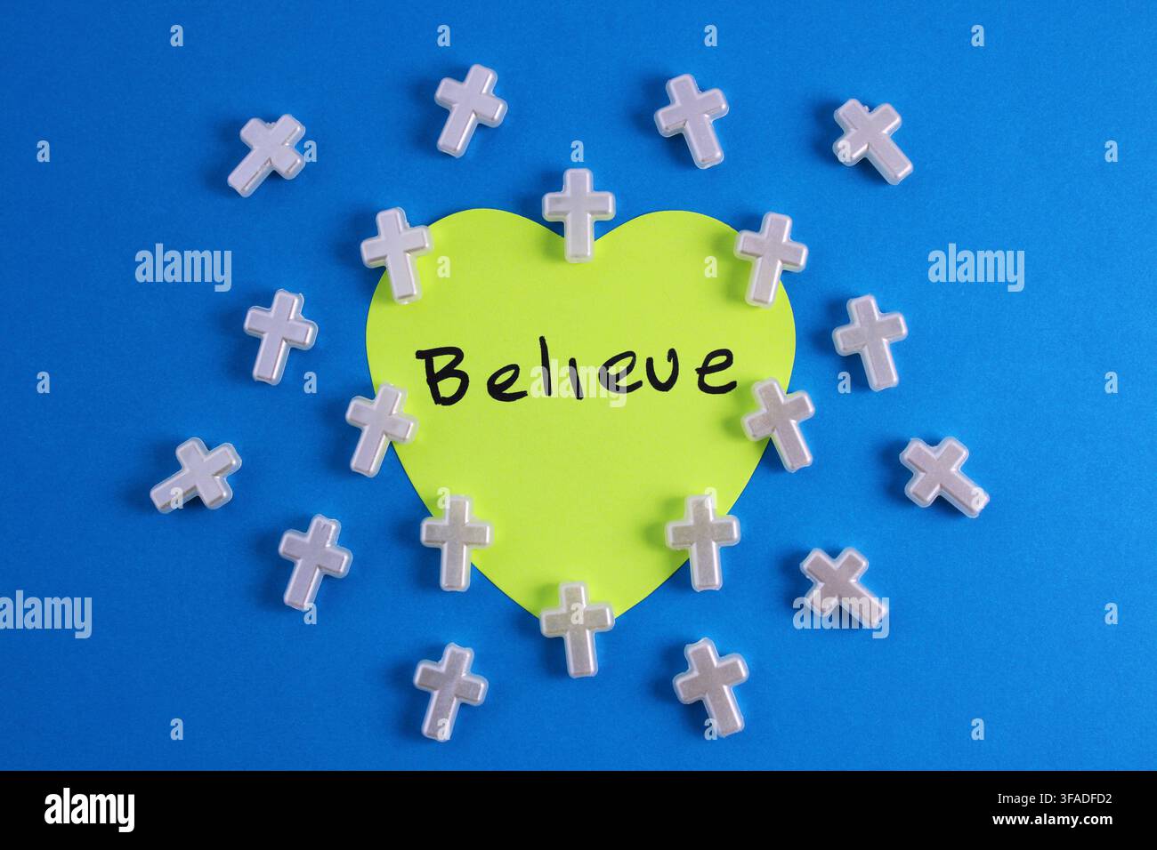 Klebezettel mit dem Wort „glauben“ umgeben von Kreuzen Stockfoto