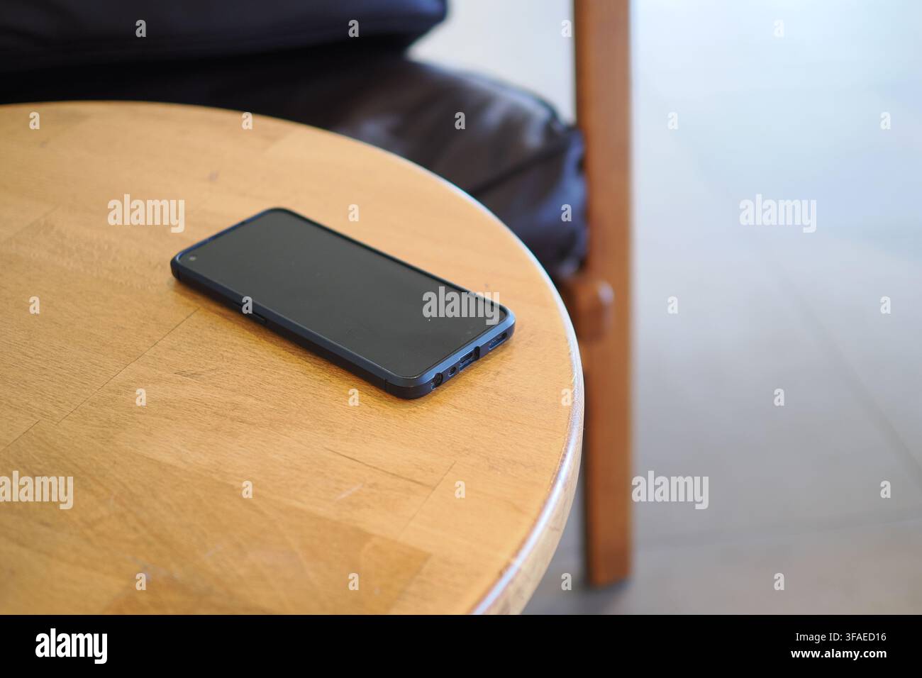 Telefon ruht auf Holztablett in einem ruhigen Café. Verlorenes Smartphone-Konzept Stockfoto