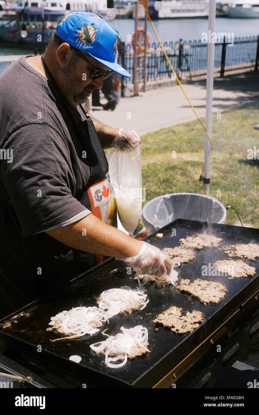 Toronto, Kanada – 20. Juni 2026: Straßenhändler grilt Zwiebeln und Burger im Freien am Wasser Stockfoto