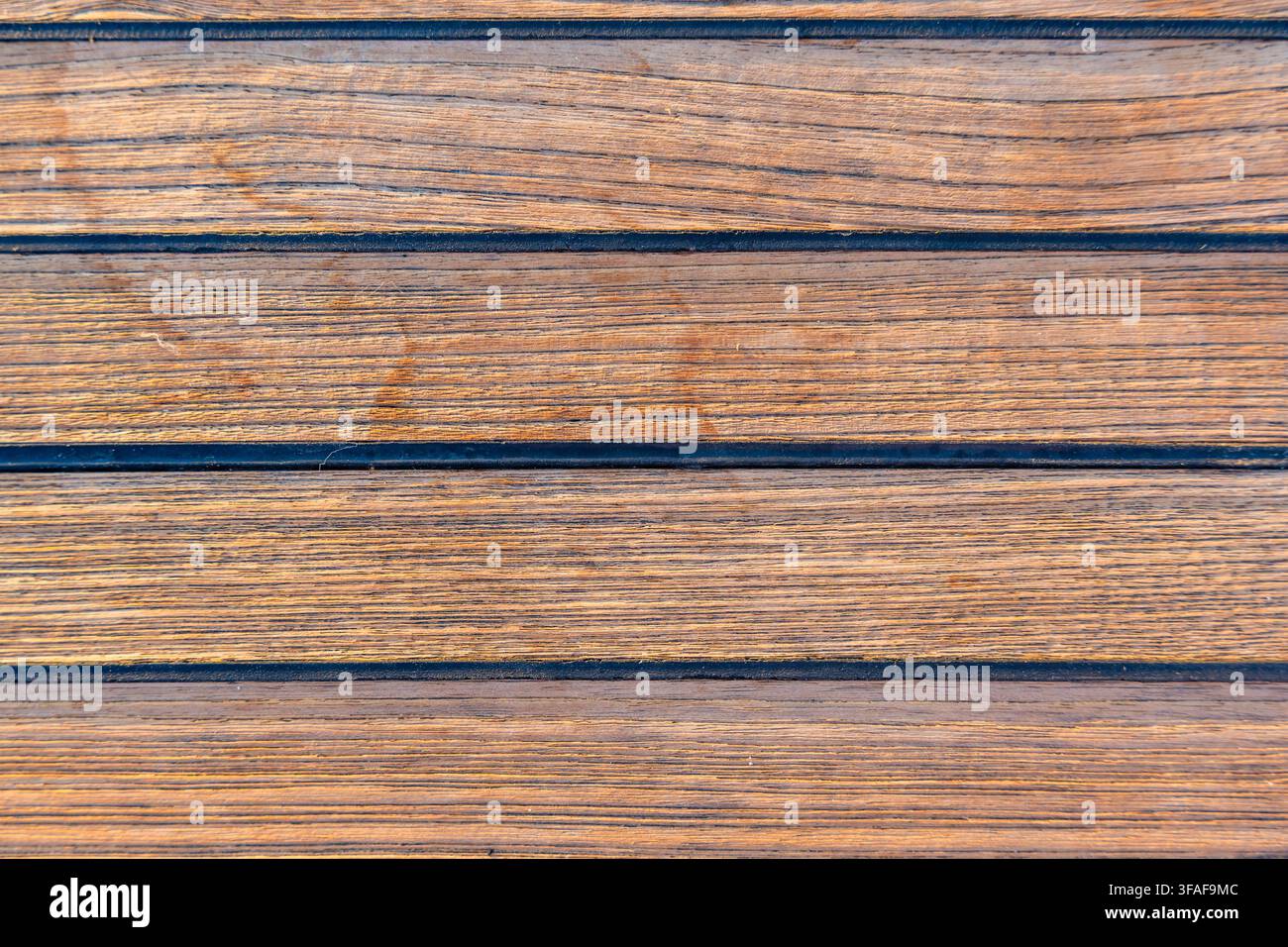 Nahaufnahme von Teakholzdecking auf einer Segelyacht, das eine saubere nautische Textur und einen nahtlosen Hintergrund erzeugt. Konzept von Marinedesign, Luxusbootfahren Stockfoto