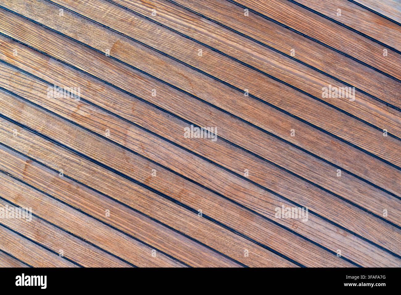 Nahaufnahme von Teakholzdecking auf einer Segelyacht, das eine saubere nautische Textur und einen nahtlosen Hintergrund erzeugt. Konzept von Marinedesign, Luxusbootfahren Stockfoto