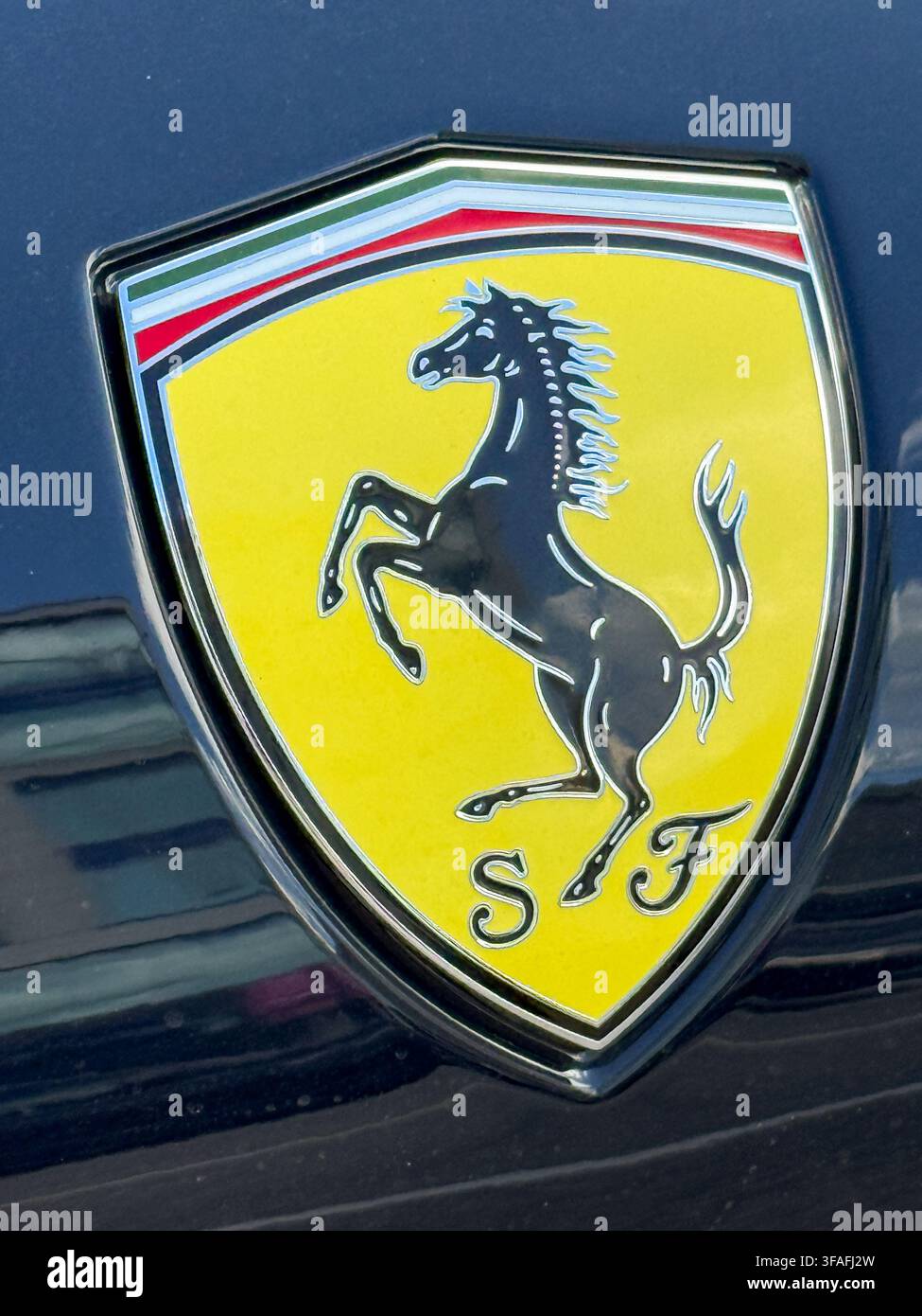 Riga, Lettland - 19. August 2026: Detaillierte Nahaufnahme des ikonischen Ferrari-Pferdeemblems, das auf einem dunklen Luxus-Sportwagen montiert ist, und hebt Italienisch hervor Stockfoto