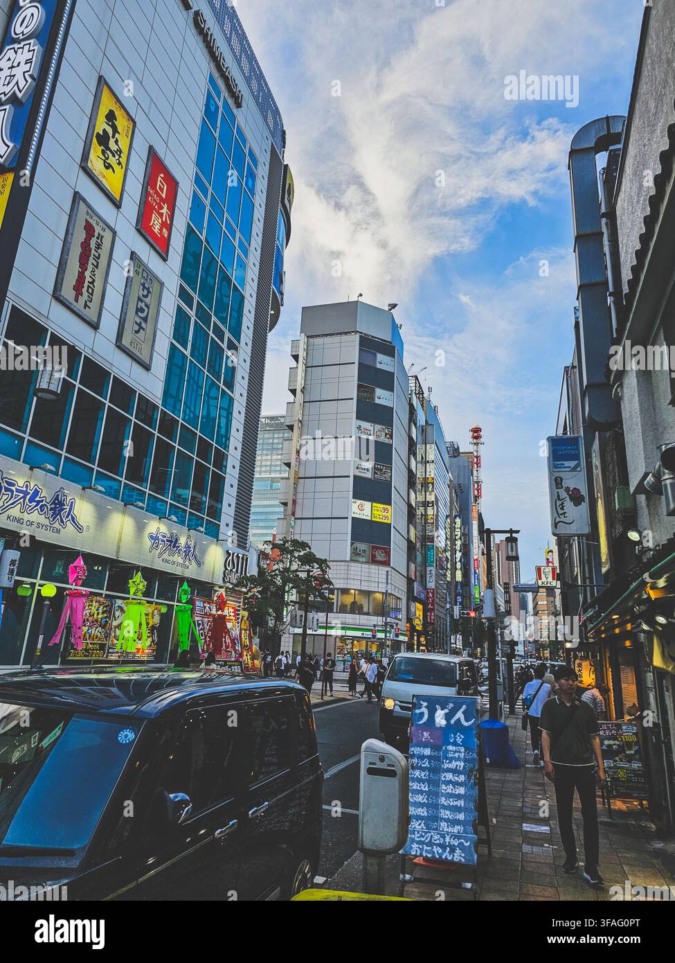 Niedrigwinkelaufnahme einer belebten Geschäftsstraße mit Schildern in der Nähe des Shimbashi-Bahnhofs in Tokio, Japan - Smartphone-aufgenommenes Stockfoto