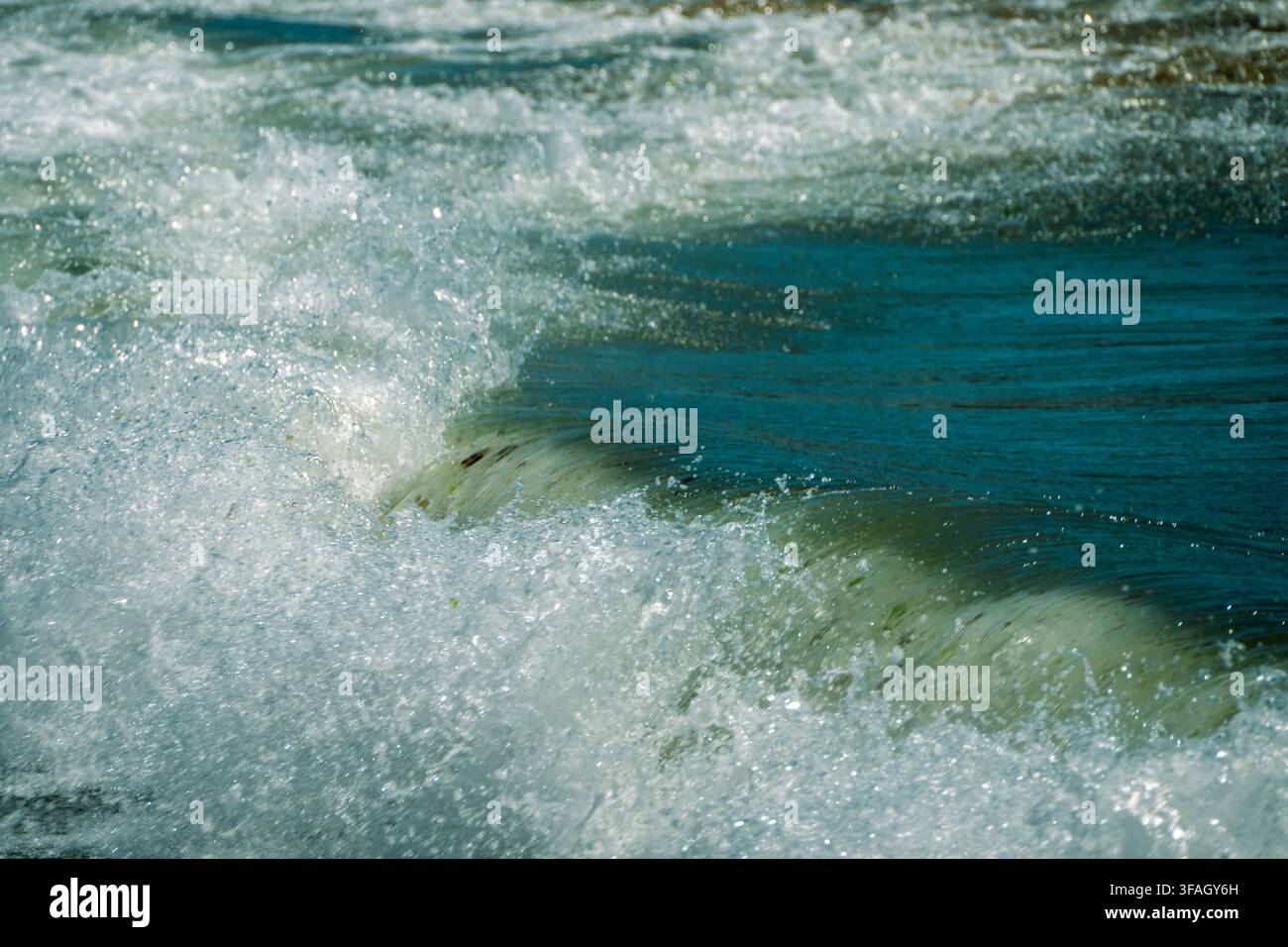 dynamische Meereswellen, die sich zu dickem weißem Schaum aufwirbeln, während sie durch tiefblaues Wasser krachen und rollen. Stockfoto