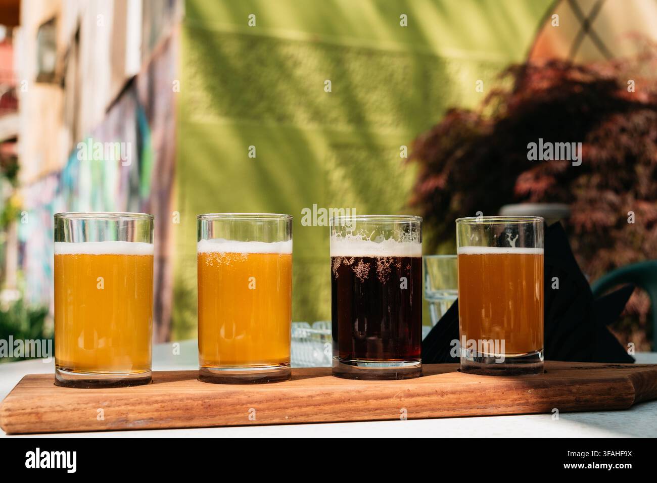 Verschiedene Craft-Bier-Proben, serviert in klaren Gläsern auf einem Holzteller. Frische Brauerei-Proben schaffen ein modernes Bar- und Verkostungskonzept. Stockfoto