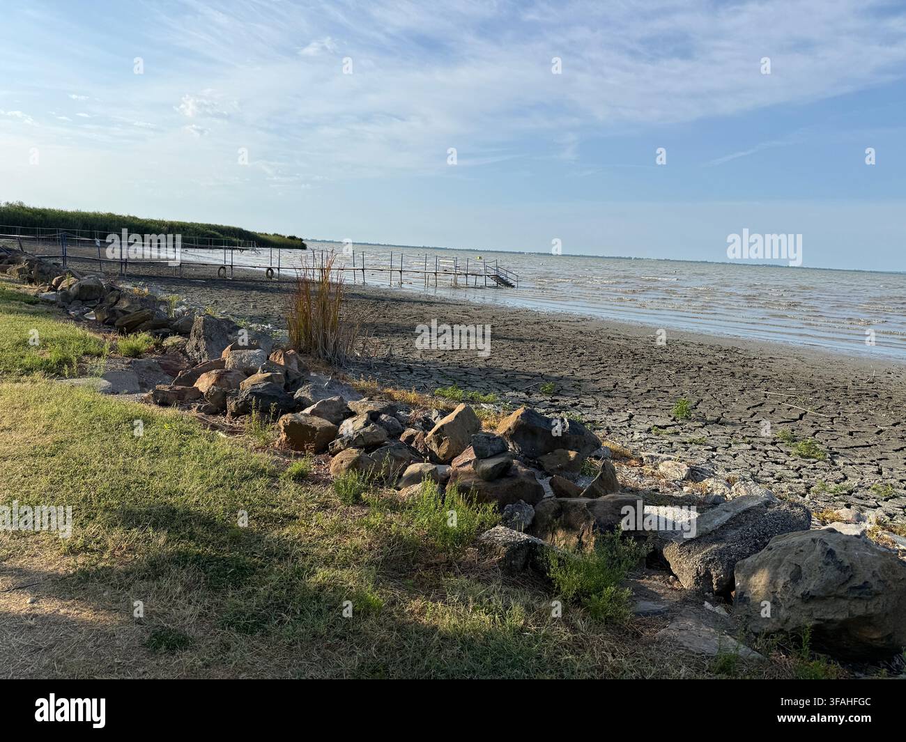 Niedriger Wasserstand und getrockneter, rissiger Schlamm am Ufer des Balaton in Badacsonylábdihegy, Ungarn - Smartphone-aufgenommenes Stockfoto