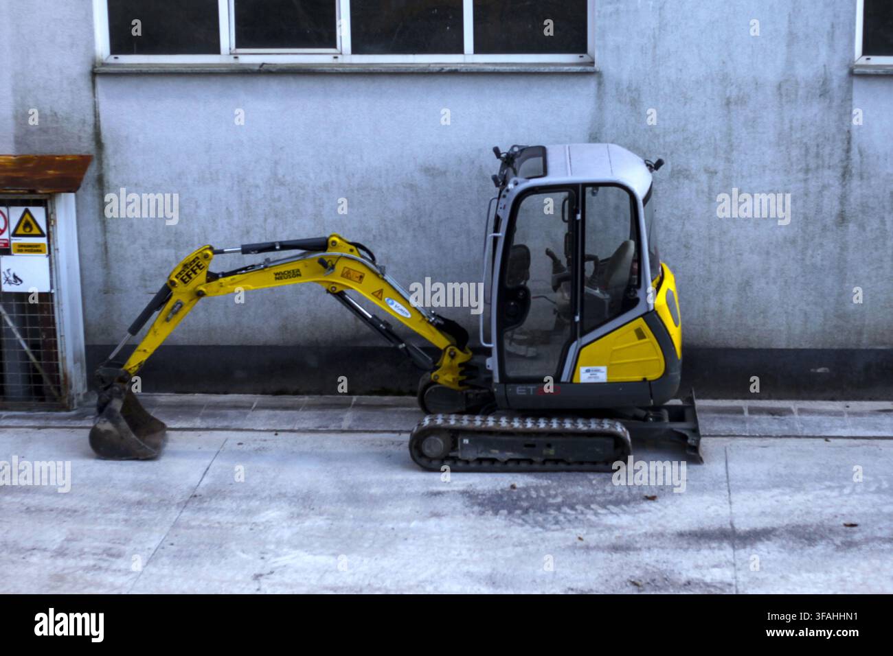Gelber Wacker Neuson EZ17 Kompakt-Mini-Bagger, der neben einer Industriewand in der Nähe einer Baustelle in Kastav, Region Kvarner, Kroatien, geparkt ist. Stockfoto