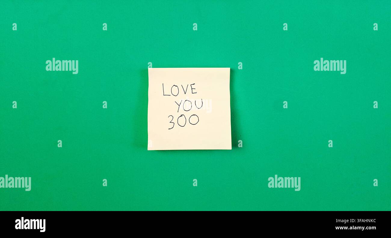 Handgeschriebene "Ich liebe dich 300"-Botschaft auf einem Klebezettel mit grünem Hintergrund Stockfoto