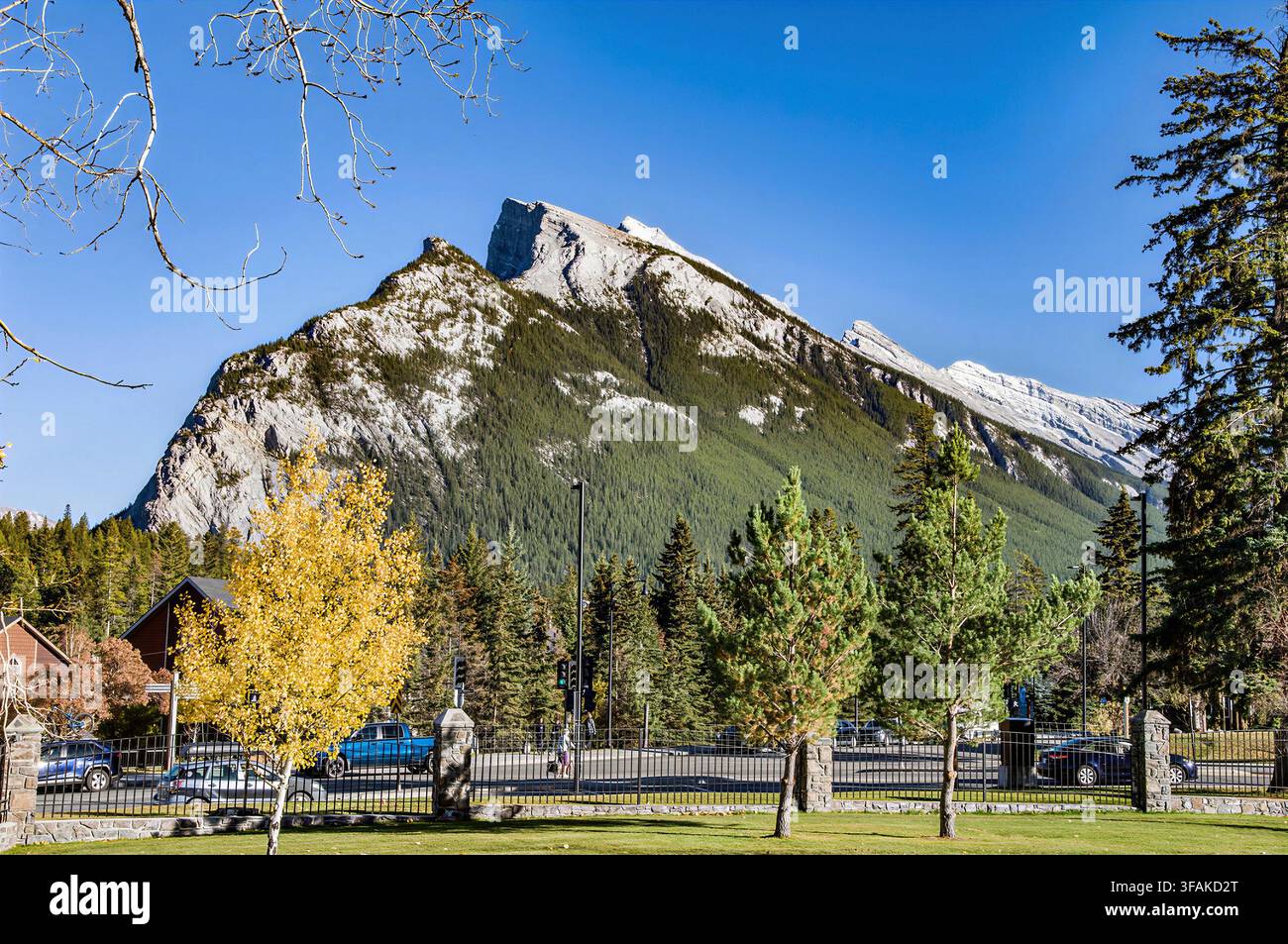 BANFF, ALBERTA, KANADA – 07. OKTOBER 2023: Ein atemberaubender Blick auf den ikonischen Gipfel des Mount Rundle, der sich über einen Kiefernwald und einen Parkplatz erhebt, eingerahmt von Herbstfarben Stockfoto