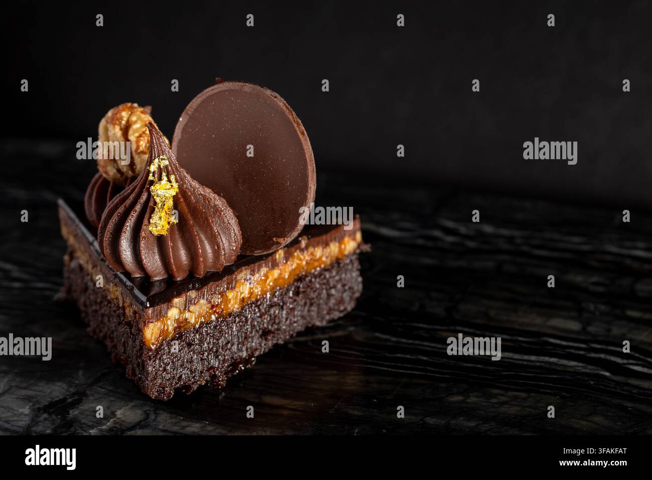 Nahaufnahme eines üppigen, schokoladigen Turtle-Brownie-Desserts auf dunklem Hintergrund Stockfoto