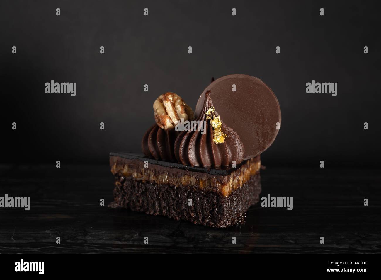 Nahaufnahme eines üppigen, schokoladigen Turtle-Brownie-Desserts auf dunklem Hintergrund Stockfoto