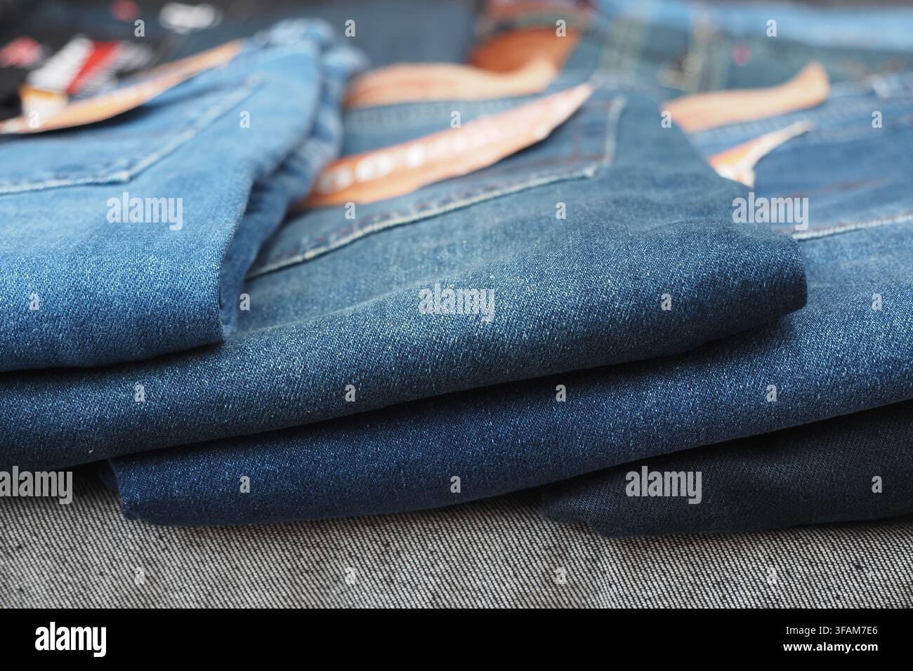 Denimjeans, die auf einem Tisch in einem Bekleidungsgeschäft gestapelt sind Stockfoto