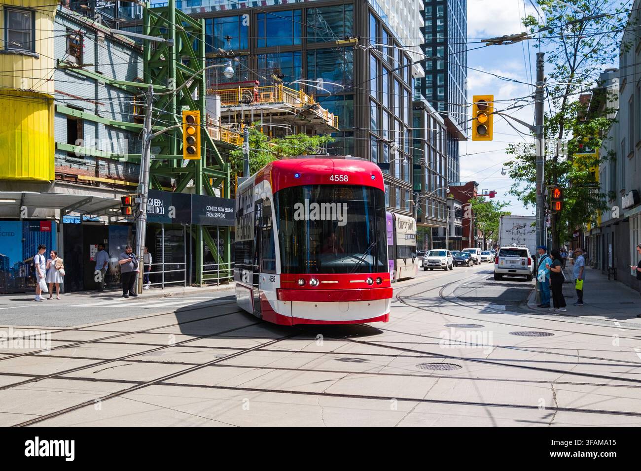 Erleben Sie die lebendige Energie der Innenstadt von Toronto, während eine Straßenbahn die belebte Kreuzung von Queen und Spadina überquert. Dieser zentrale Knotenpunkt präsentiert Stockfoto