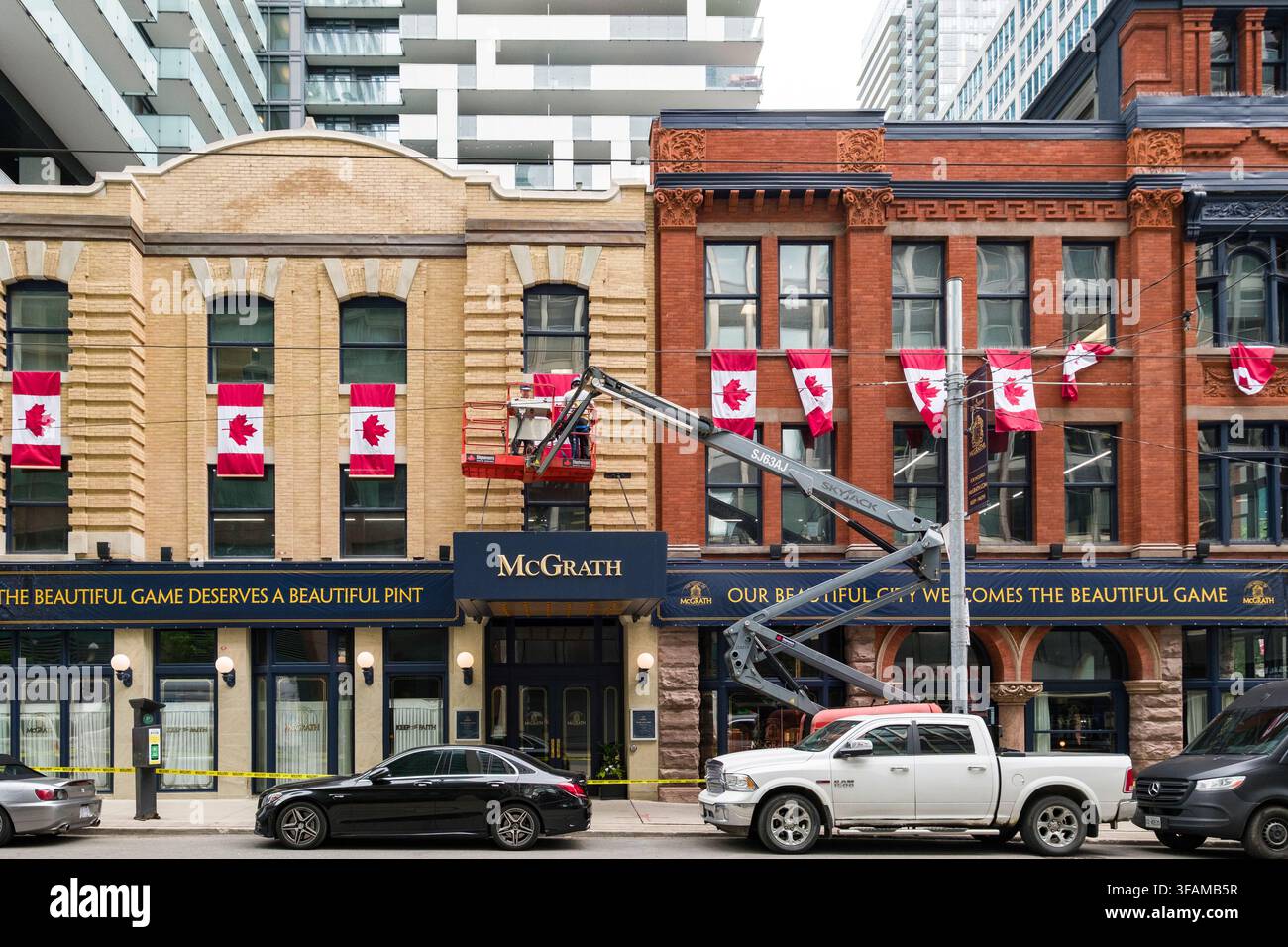 In der Herz der Stadt Toronto, Ontario, aufgenommen, zeigt diese Straßenansicht ein traditionelles Backsteingebäude, das mit kanadischen Flaggen geschmückt ist. Das Gebäude, namens Mc Stockfoto