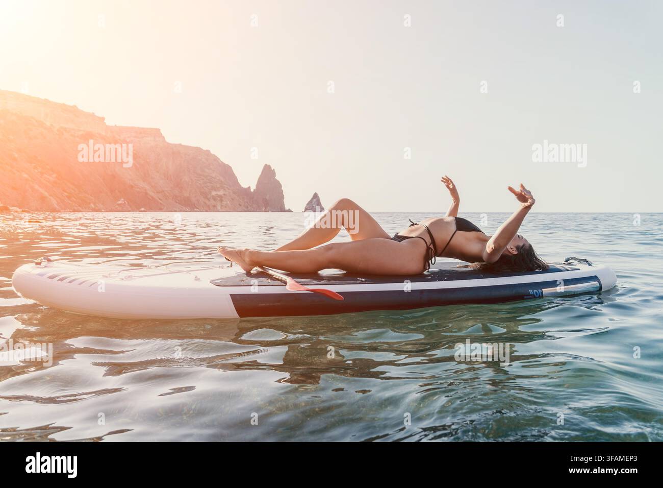 Frau auf Stand Up Paddleboard entspannt am Strand mit Meereslandschaft Stockfoto