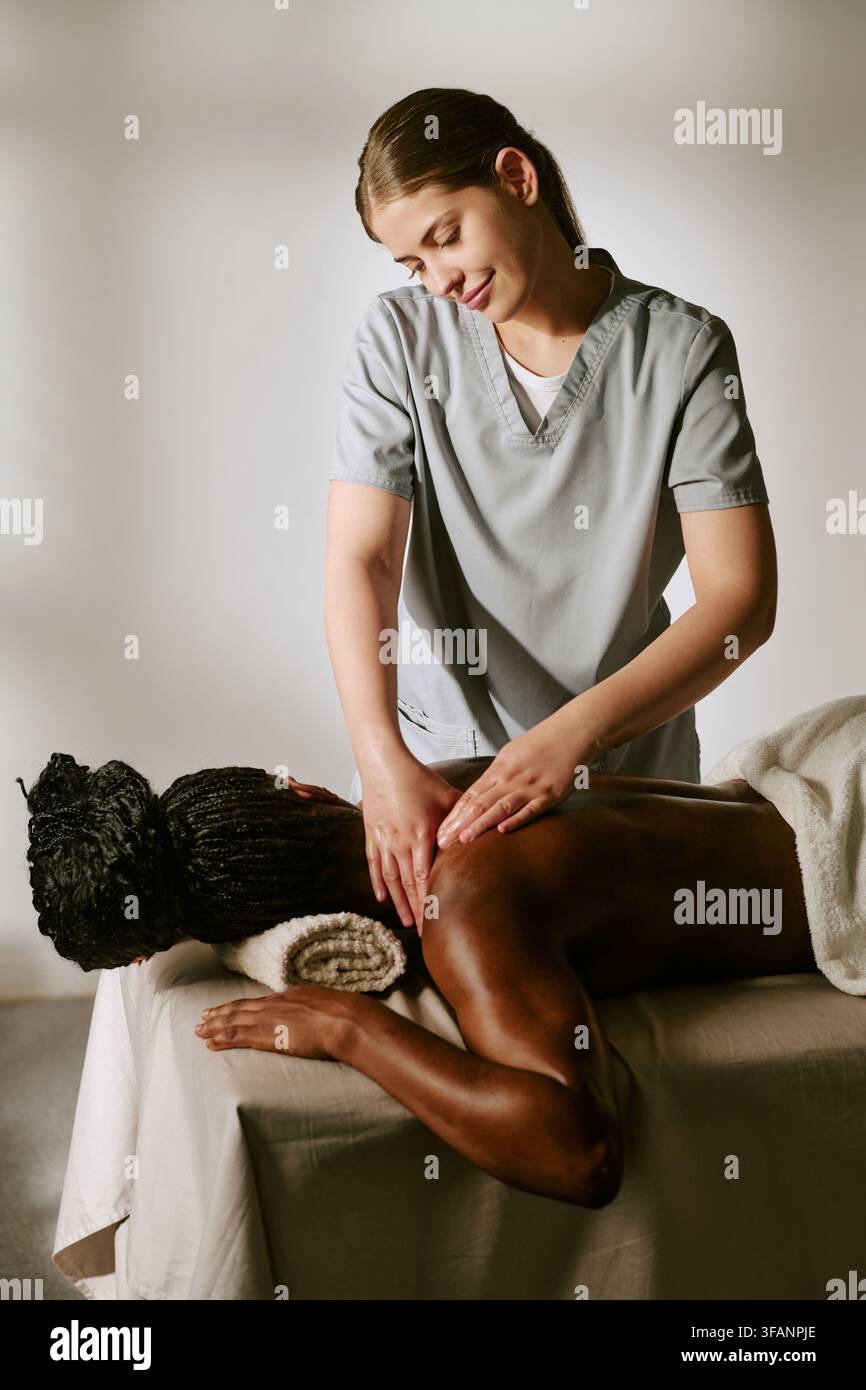 Frauenmassagetherapeutin massiert den Rücken einer schwarzen Frau in einem Spa-Salon Stockfoto
