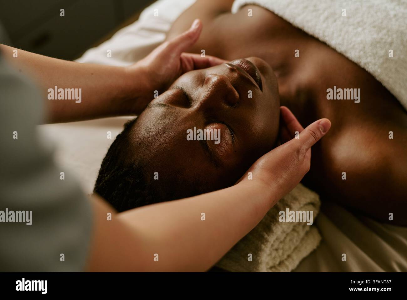 Schwarze Frau erhält entspannende Gesichtsmasage in einem Wellness-Spa Stockfoto