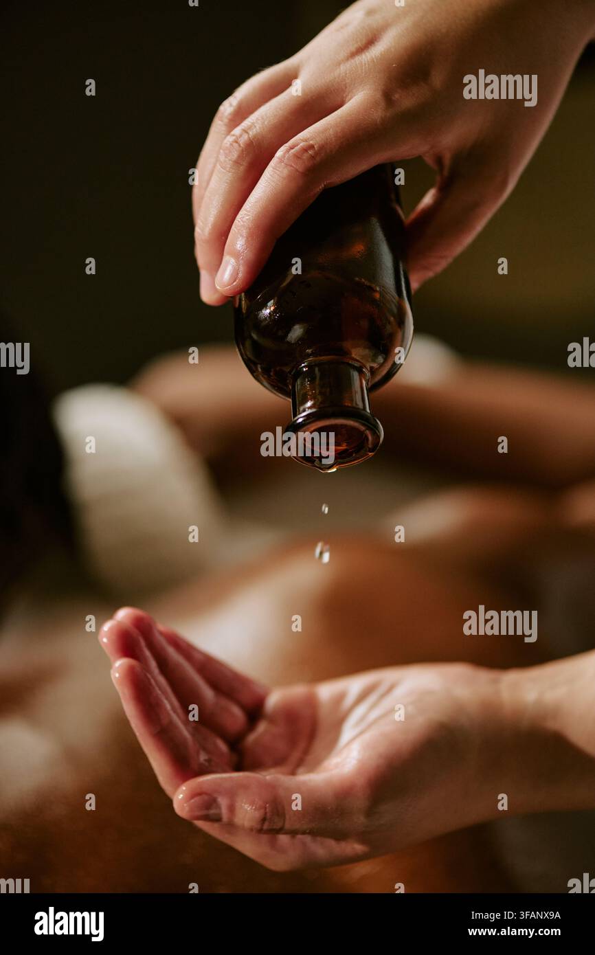 Massagetherapeutin gießt ätherisches Öl auf die Hand für eine Rückenmassage Stockfoto