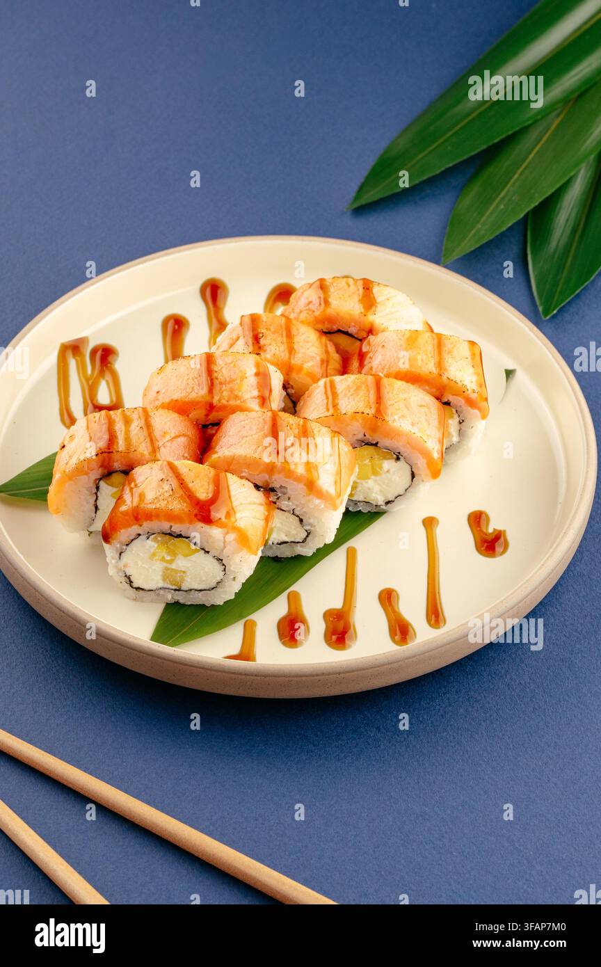 Geschmorte Lachs-Sushi-Rollen auf Teller mit Sauce zum Beträufeln Stockfoto