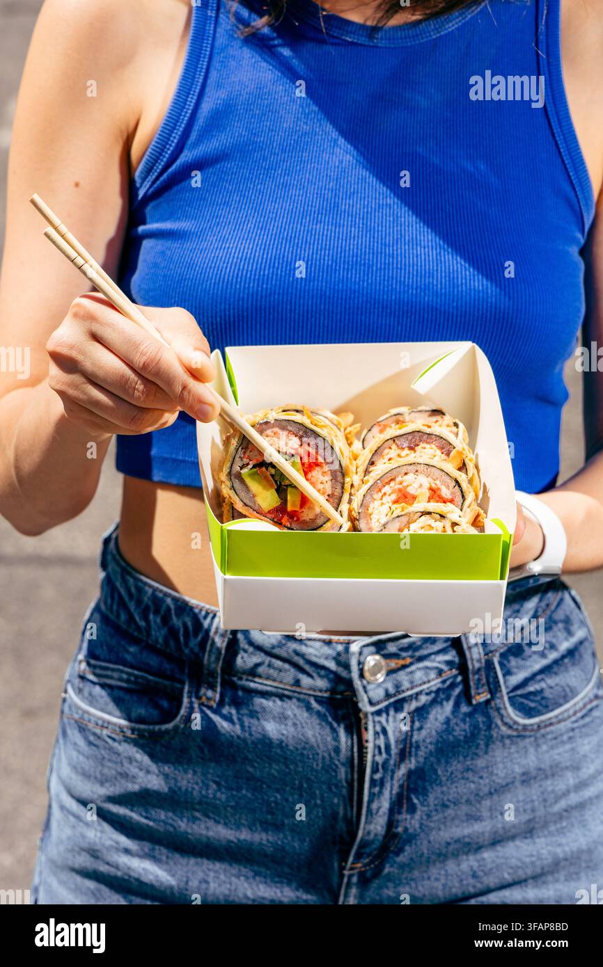 Junge Frau isst Sushi aus einer Takeaway-Box Stockfoto