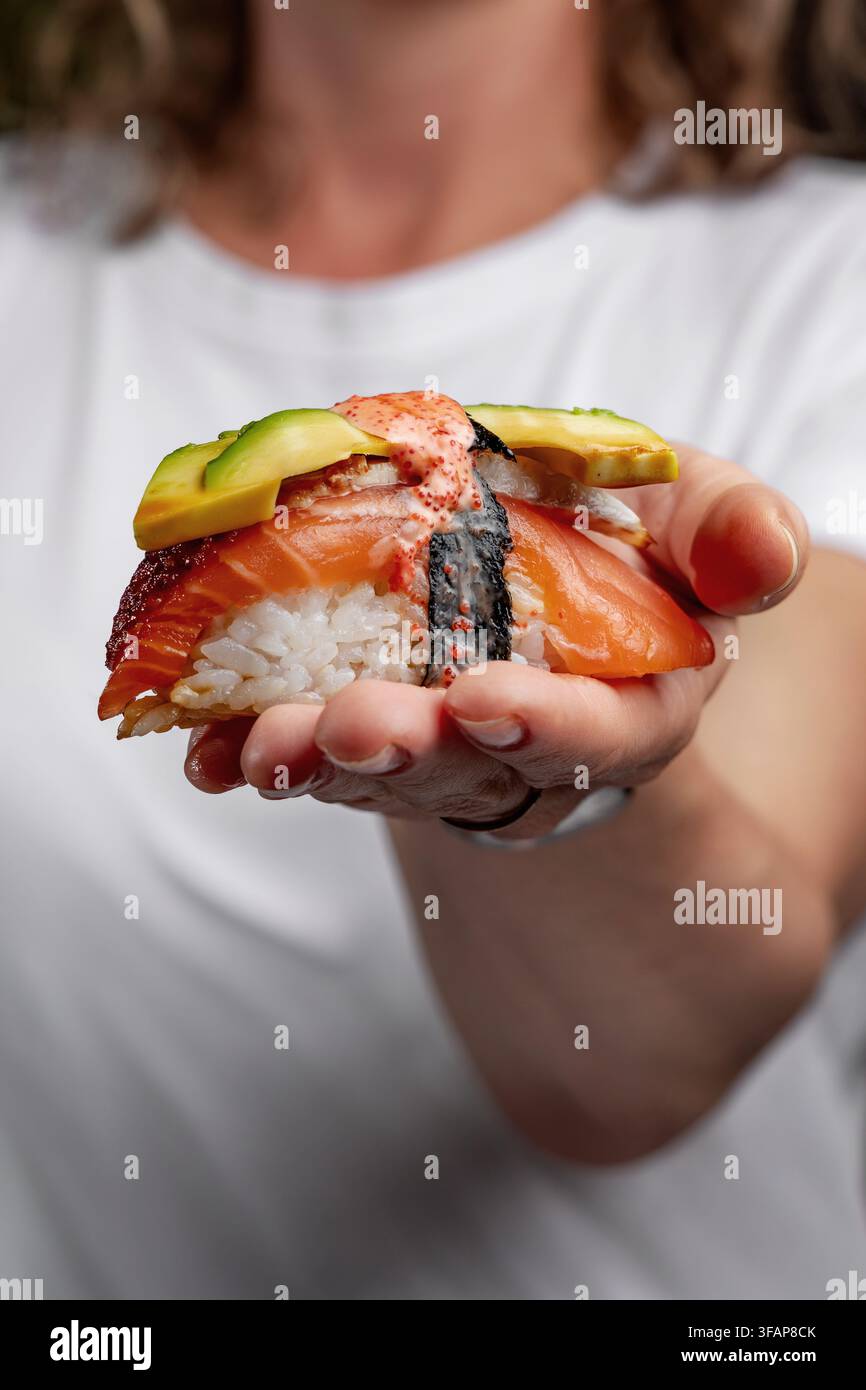 Frau hält ein großes Stück Design-Sushi Stockfoto