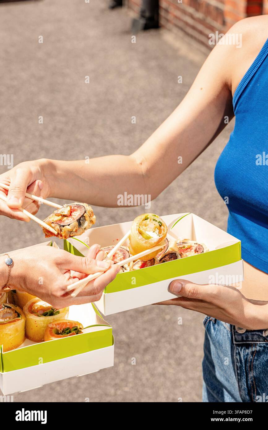 Zwei Personen teilen und essen Takeaway-Sushi Stockfoto