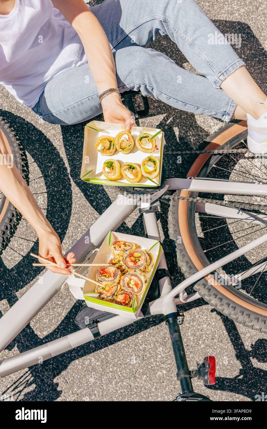 Freunde teilen sich Sushi zum Mitnehmen bei einer urbanen Fahrradpause Stockfoto