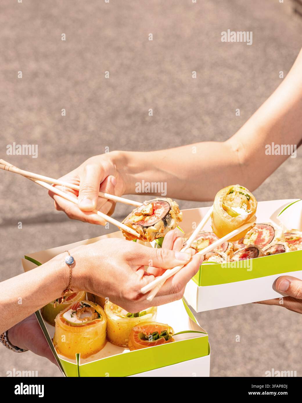 Freunde teilen Sushi mit Stäbchen aus Schachteln Stockfoto