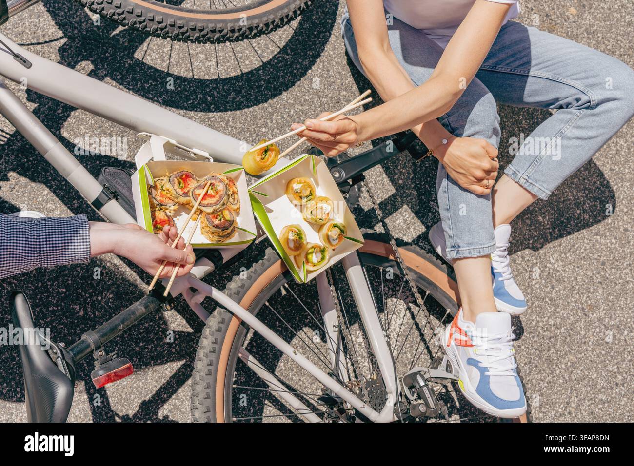 Menschen, die Takeaway-Sushi neben einem Fahrrad essen Stockfoto