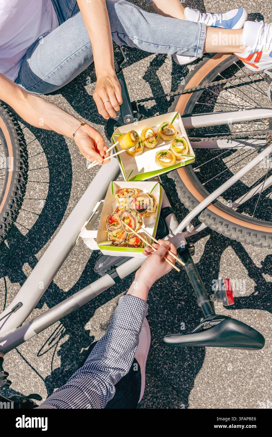 Menschen, die Takeaway-Sushi neben einem Fahrrad essen Stockfoto