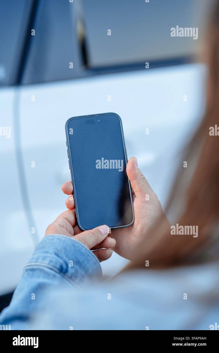 Frau in Jeansjacke hält ein Smartphone Stockfoto