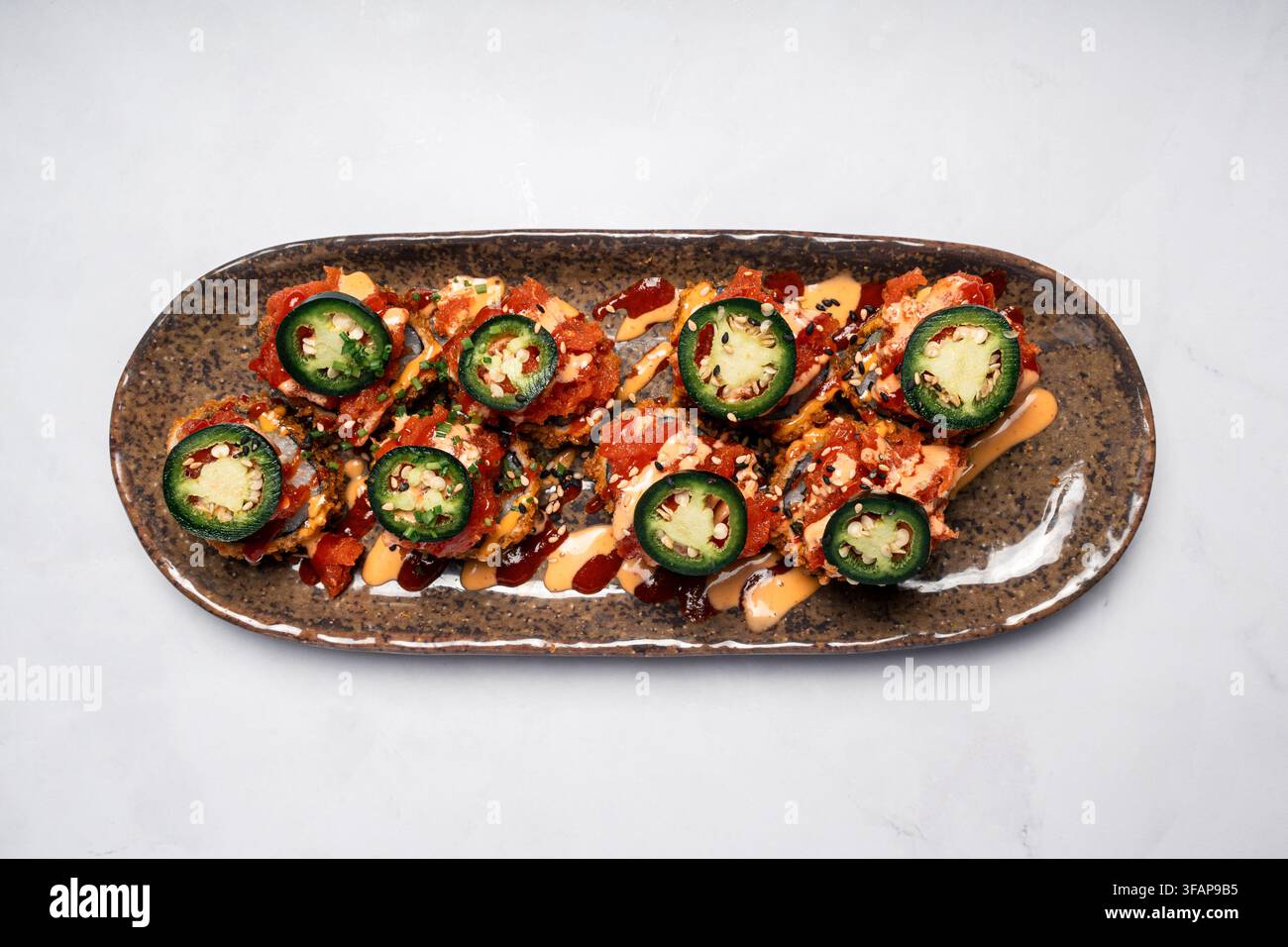 Scharfe Thunfisch-Sushi-Rollen mit frischem Jalapeño-Topping Stockfoto