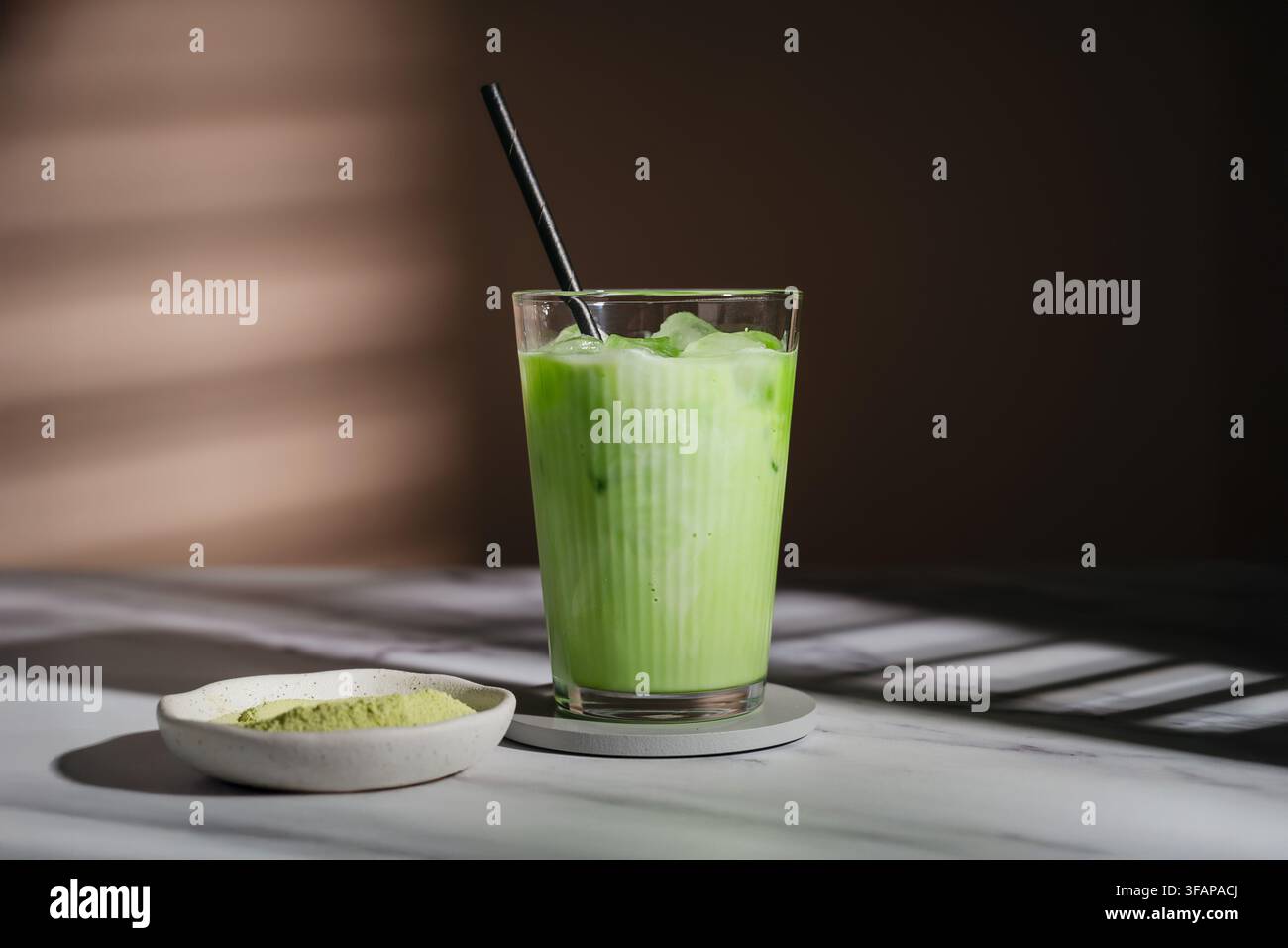 Eis-Matcha-Latte mit Papierstrohhalm auf einer Marmorarbeitsplatte Stockfoto