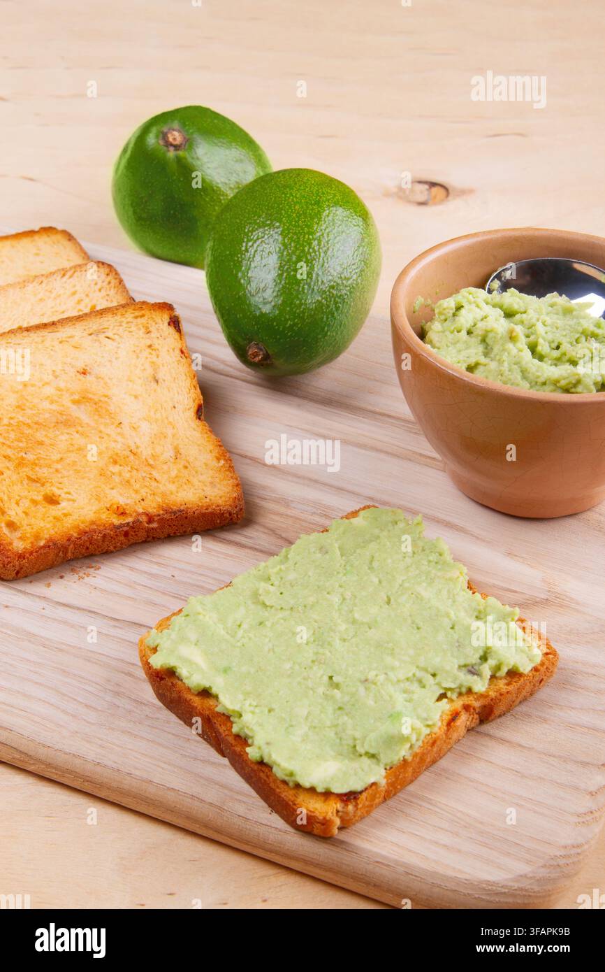 Gesunder Frühstückstoast mit Avocado-Püree auf Holzunterlage, Nahaufnahme Stockfoto