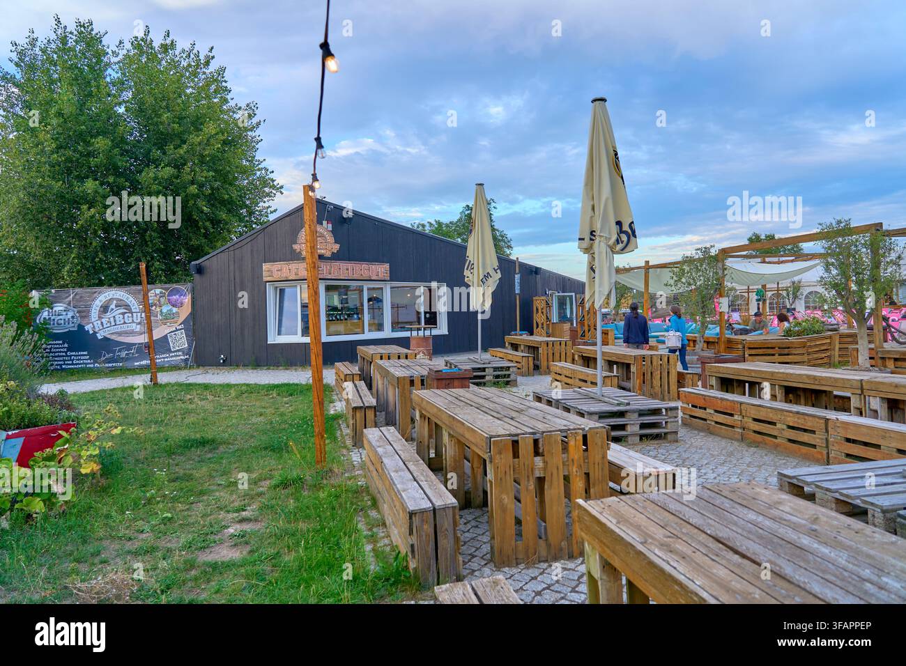 Vorübergehender Urbanismus und Upcycling-Kultur gedeihen bei Treibgut Magdeburg, wo Outdoor-Palettenmöbel moderne Freizeitgastronomie repräsentieren, die popula Stockfoto