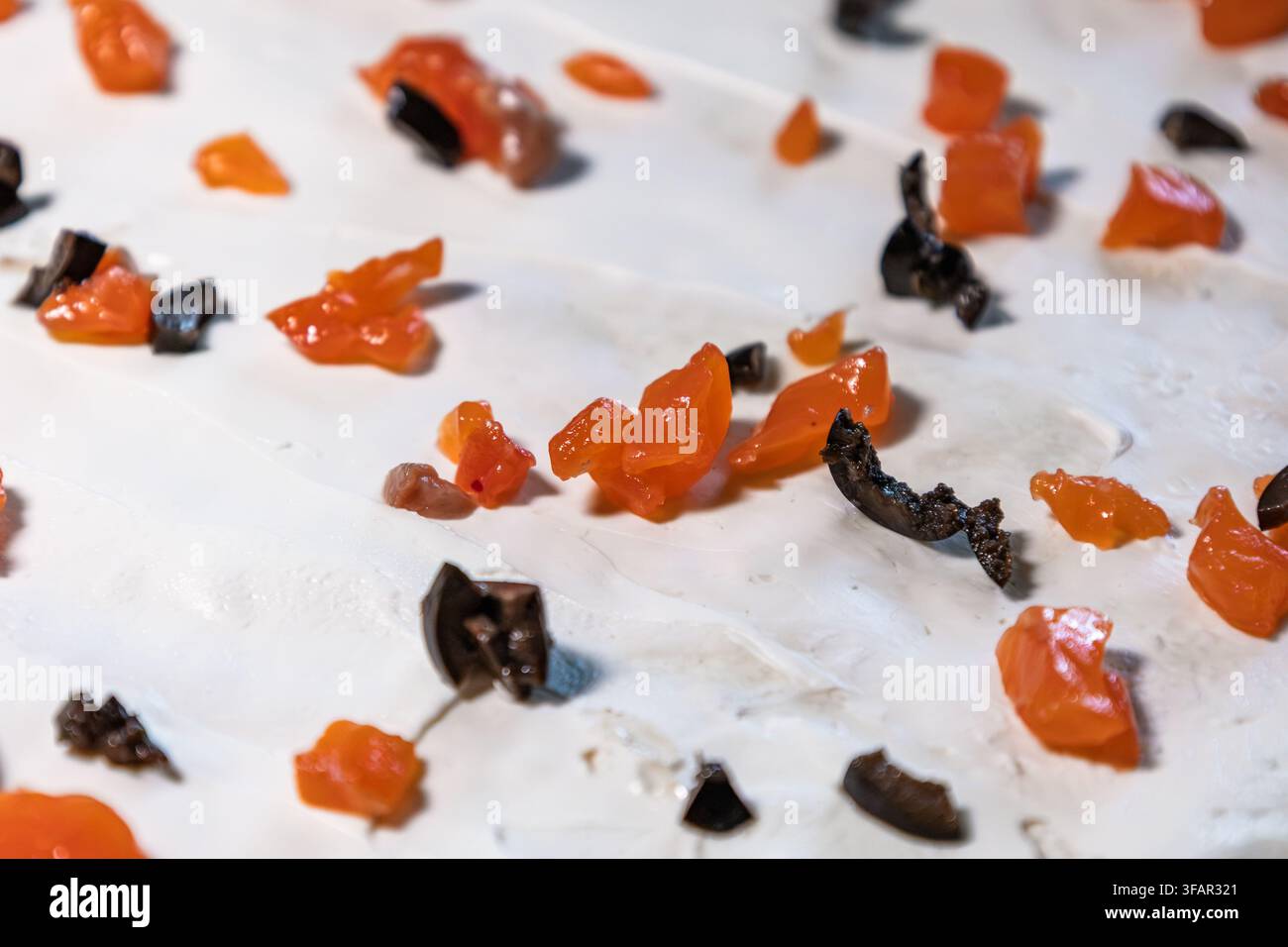Eine Nahaufnahme von weichem Frischkäse, der auf Pitabrot gestrichen ist, mit Stücken gesalzenem Roter Fisch und schwarzen Oliven im Innenraum, bei der Zubereitung einer Gourmet-Fischrolle Stockfoto