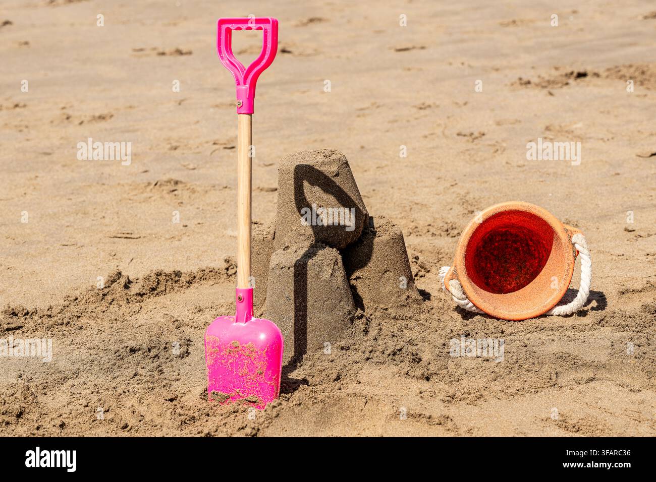 Stilleben am Meer, Eimer und Schaufel neben einem Sandburg des Kindes Stockfoto