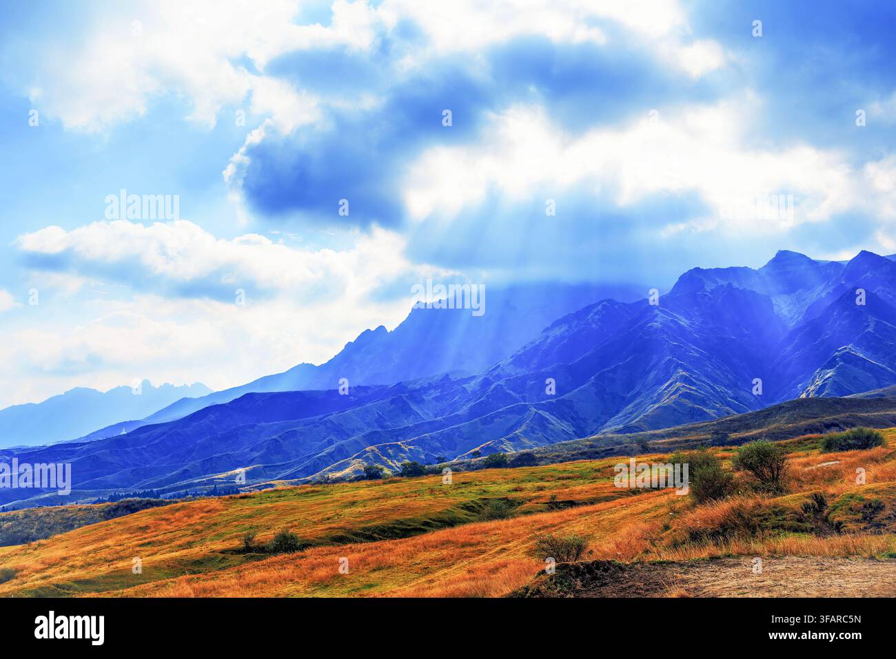 Sonnenstrahlen brechen durch die Wolken und erleuchten Herbsthügel in Aso, Präfektur Kumamoto, Kyushu, Japan Stockfoto